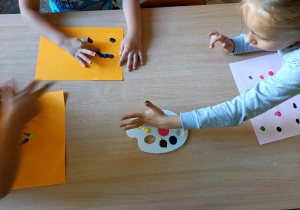 Dzieci malują zakropkowane obrazy palcami zamoczonymi w farbie